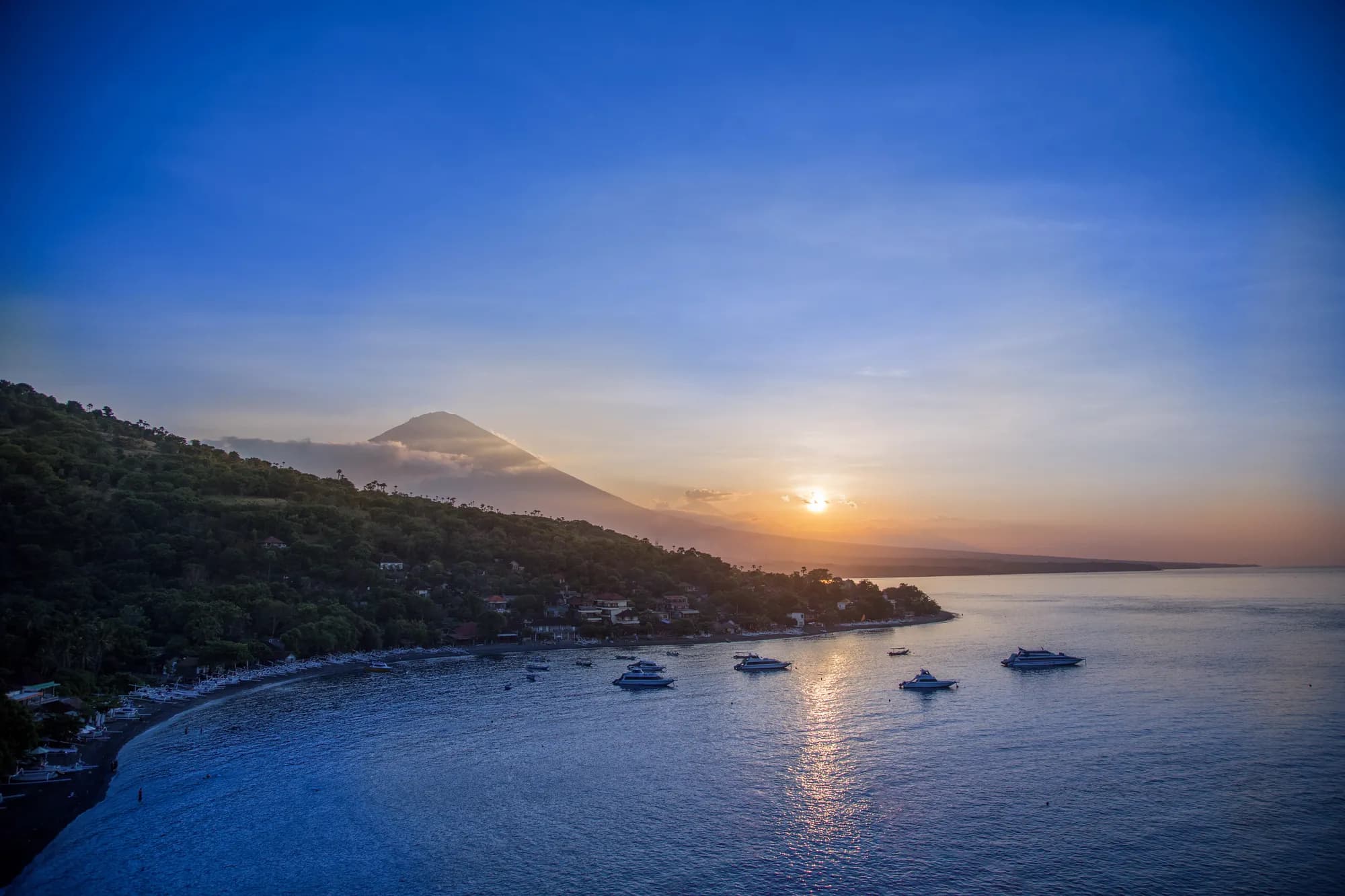 Baie d’Amed au coucher du soleil, bateaux et mont Agung, à Bali
