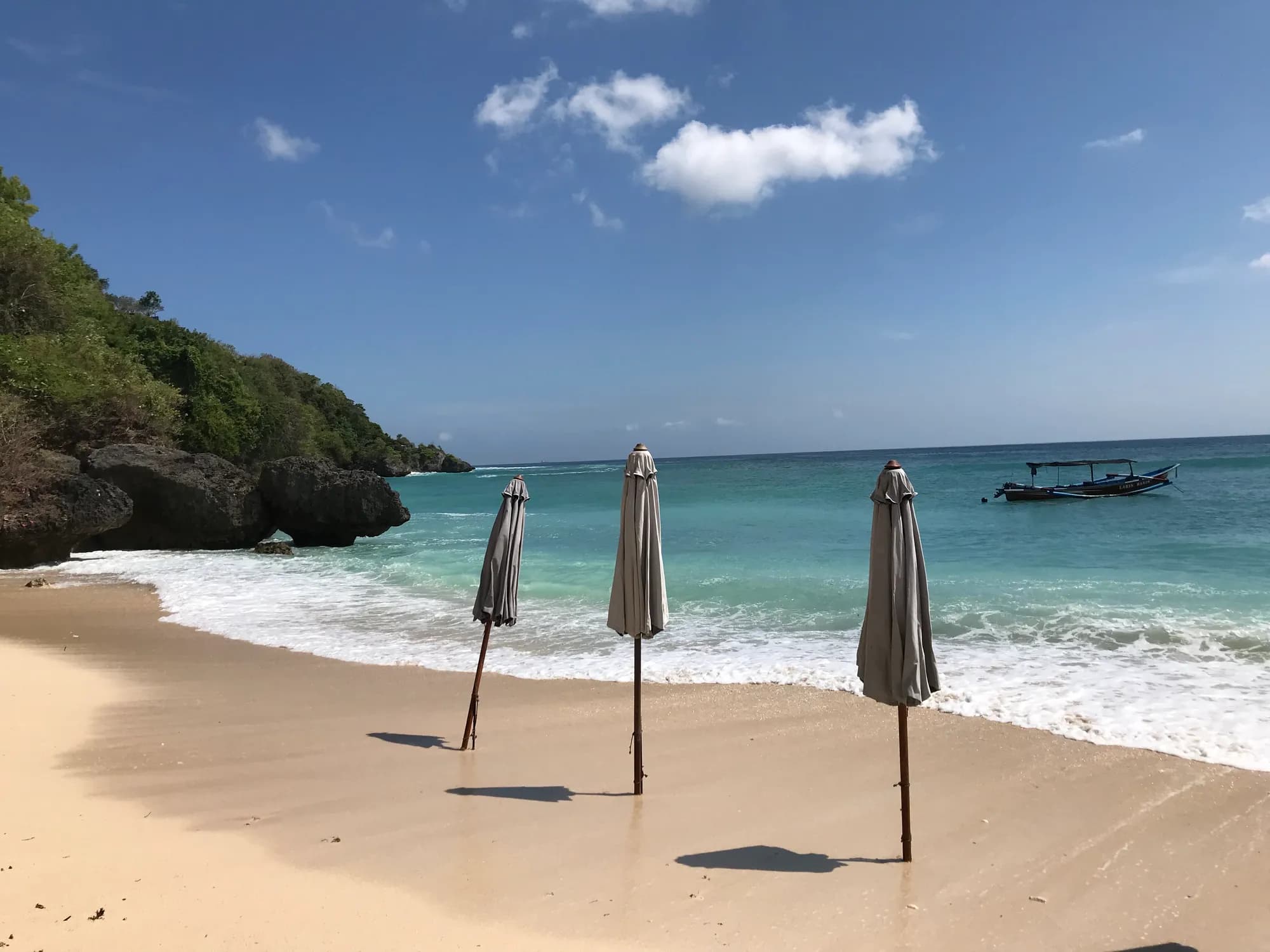 Crique de Padang Padang, sable, falaises et bateau, à Pecatu, Bali